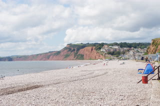 Playa de guijarros junto al pueblo y los acantilados rojos
